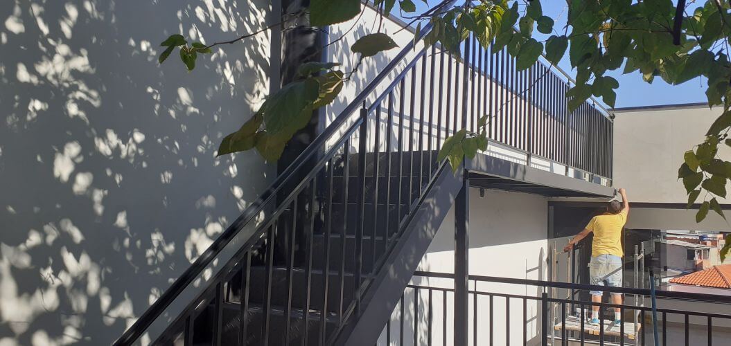 Escada metálica com estrutura preta e degraus de madeira em residência